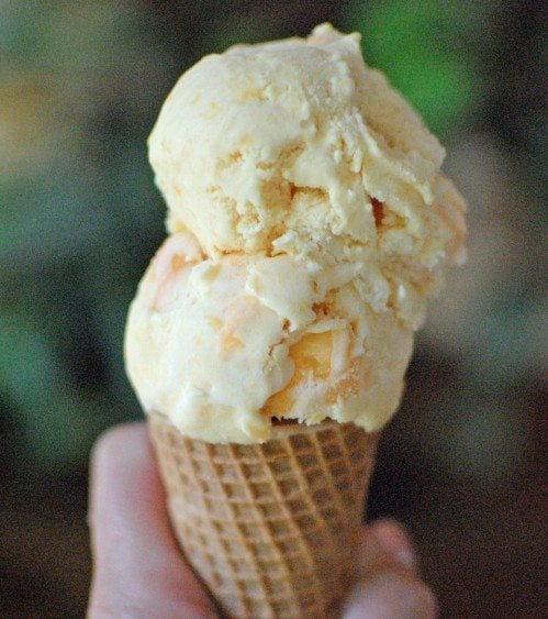 Homemade peach ice cream in an ice cream cone.