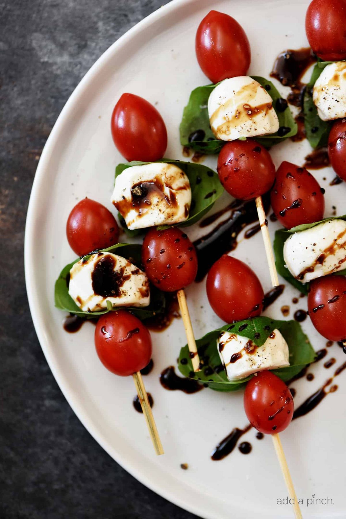 Caprese Salad Skewers drizzled with balsamic on a. plate.