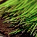 roasted asparagus recipe with asparagus lying on brown board.