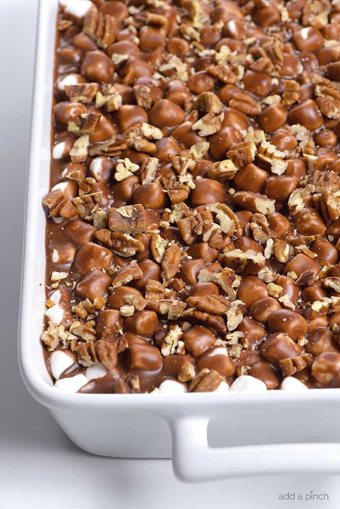 White porcelain dish with handles holds cake topped with pecans, marshmallows and chocolate icing  // addapinch.com