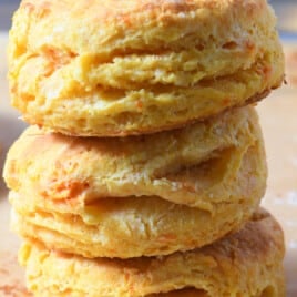 Three sweet potato biscuits stacked on a baking sheet lined with parchment paper.