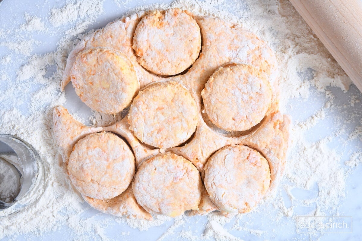 Cut sweet potato biscuits on a floured marble surface.
