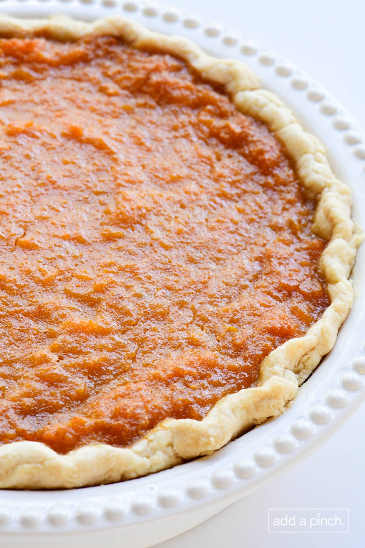 Photograph of baked sweet potato pie on white background. 