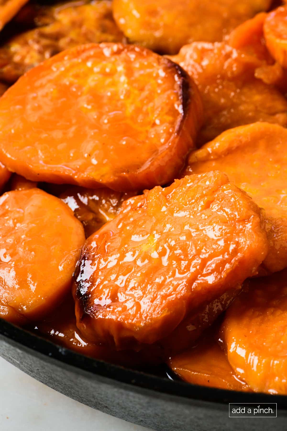 Candied sweet potatoes in a cast iron skillet on a marble countertop.