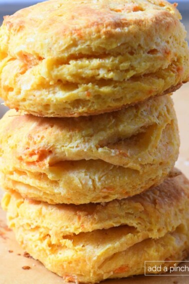 Three sweet potato biscuits stacked on a baking sheet lined with parchment paper.