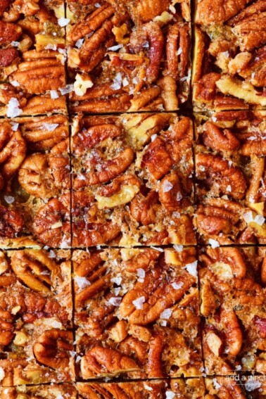 Pecan pie bars cut into individual squares sprinkled with flakey salt.