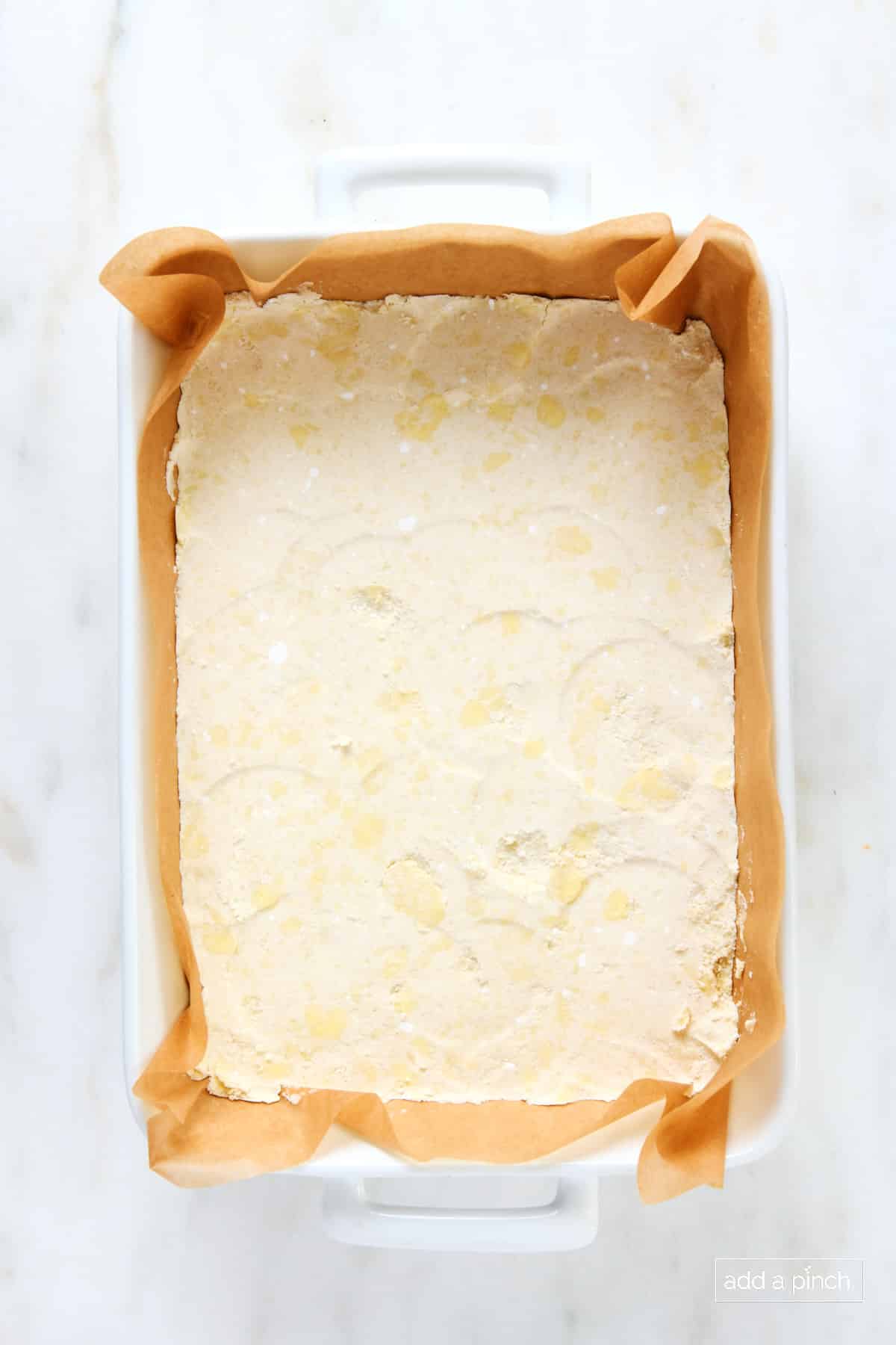 Shortbread crust in a parchment-lined baking dish.