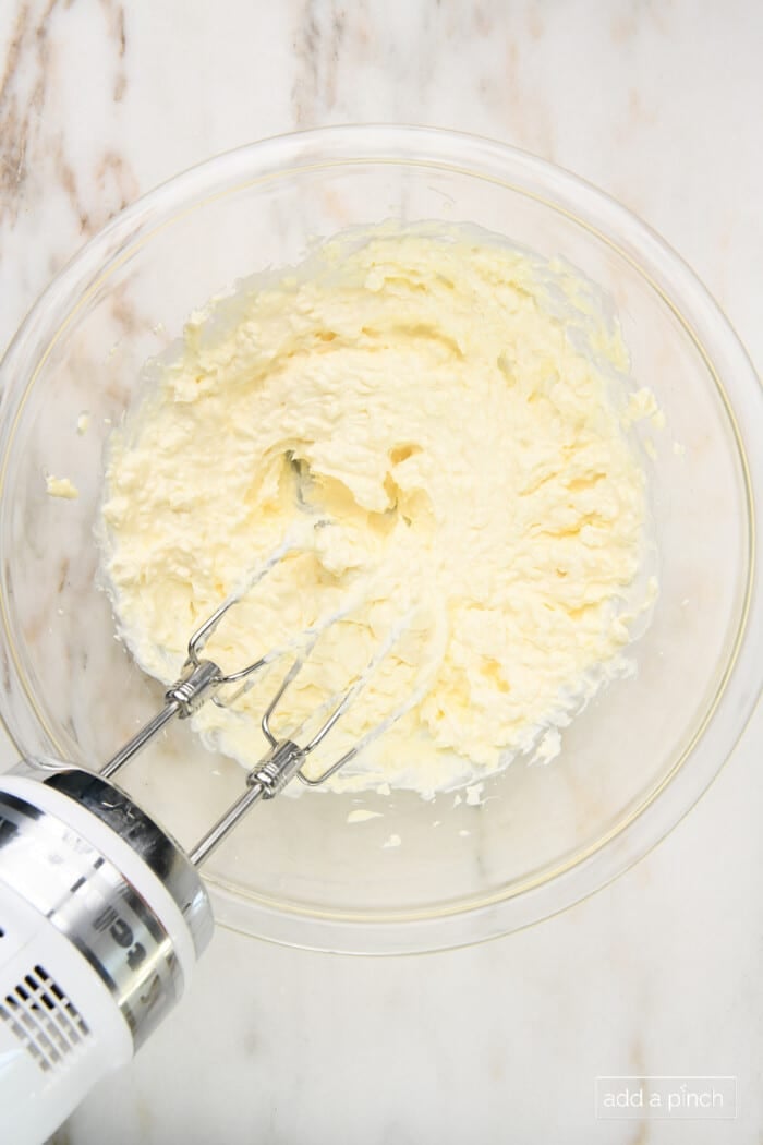 Mixing cream cheese and sour cream in a glass bowl