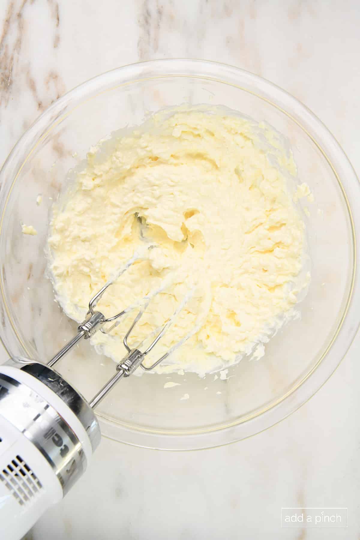 Mixing cream cheese and sour cream in a glass bowl