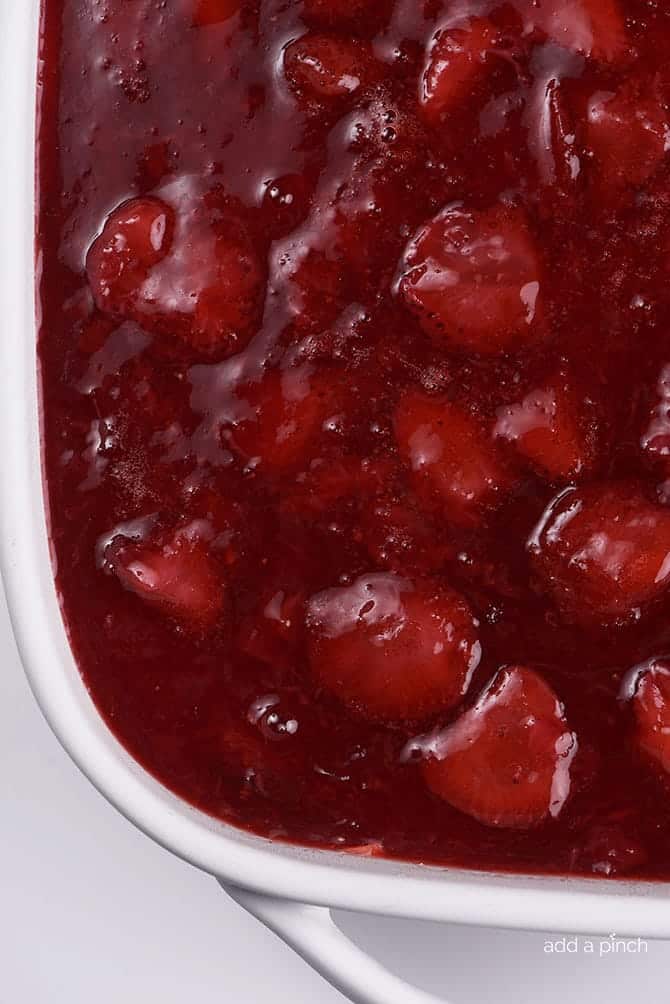 White baking dish with handles with strawberry jello topping.