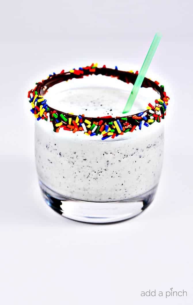 Mint Chocolate Chip Milkshakes make a fun treat anytime, especially for the mint chocolate chip lover. Add a fun rainbow rimmed glass for even more fun to your milkshake! // addapinch.com
