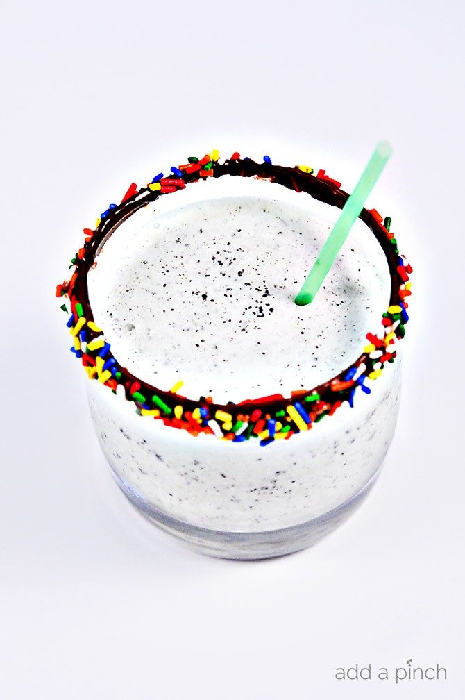 Mint Chocolate Chip Milkshakes make a fun treat anytime, especially for the mint chocolate chip lover. Add a fun rainbow rimmed glass for even more fun to your milkshake! // addapinch.com
