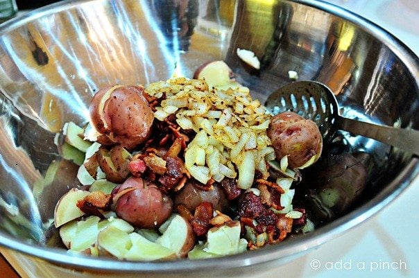 Stainless bowl with potatoes, bacon and onion to make warm potato salad.