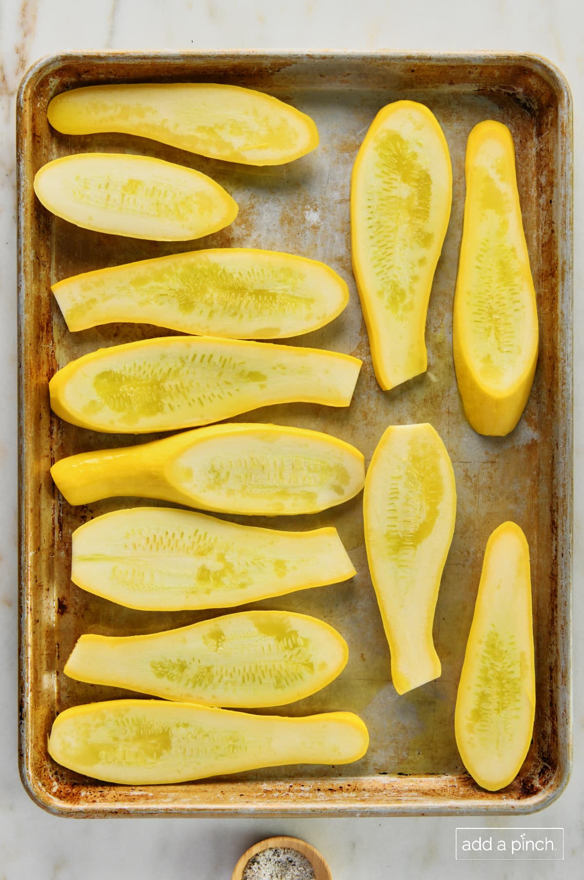 Photo of squash with olive oil on a baking sheet.