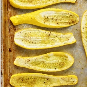 Roasted squash on a baking sheet on a marble surface.