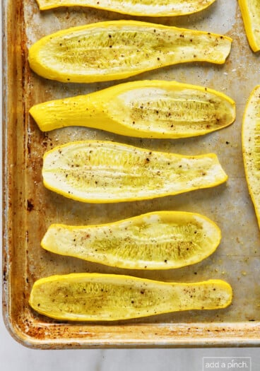 Roasted squash on a baking sheet on a marble surface.