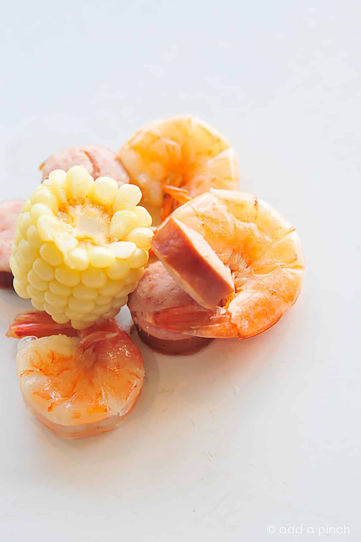 Photo of shrimp and corn on a white surface.