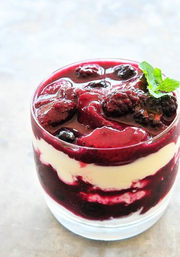 Photo of Triple Berry Parfait in a clear glass topped with a sprig of mint. // addapinch.com