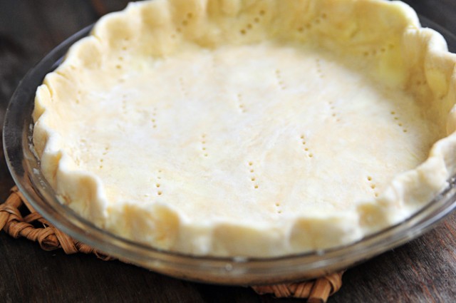 Fluted pie crust with holes pricked into bottom in glass pie plate.  // addapinch.com