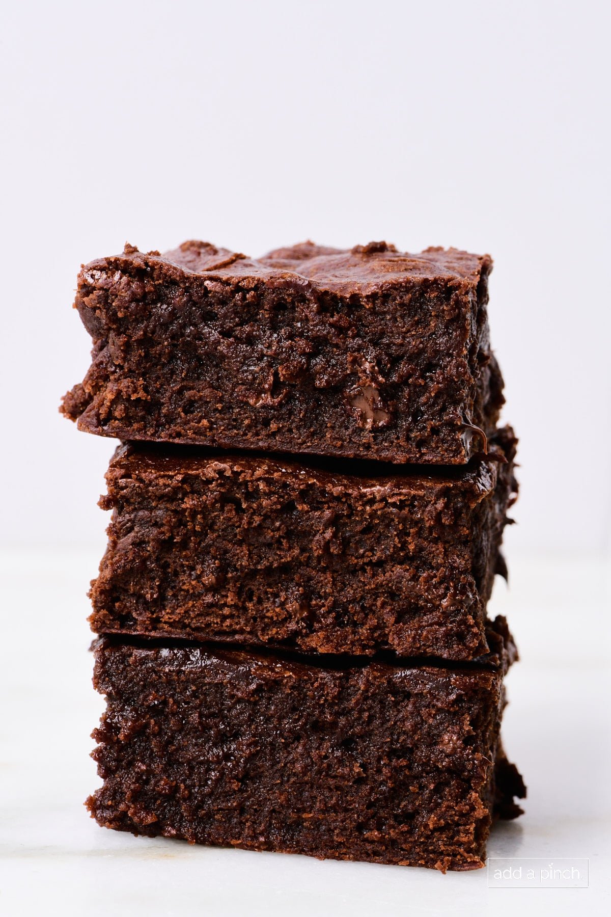 Stack of the best brownies on a marble countertop with a white background.
