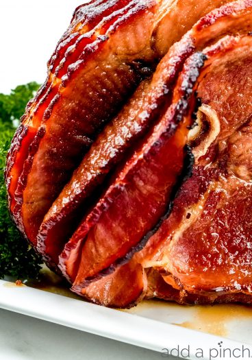 Photograph of cooked ham on a white platter.