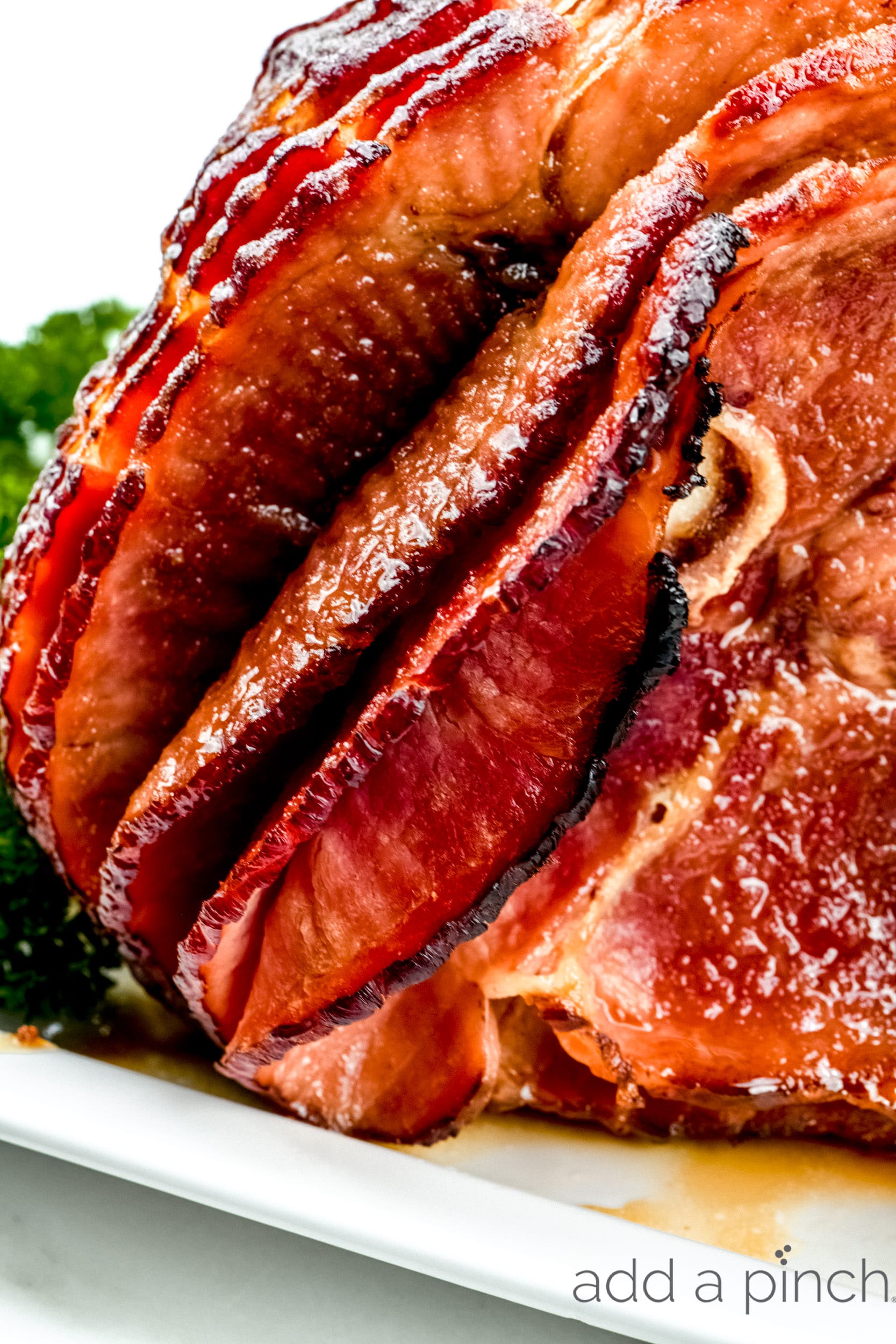 Photograph of spiral sliced baked ham on a white platter. 