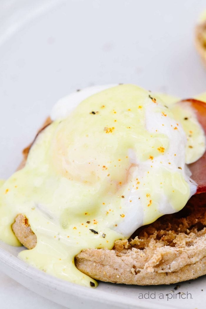 Eggs Benedict Recipe - Toasted English muffins topped with ham, bacon, or Canadian-style bacon, and poached eggs and then drizzled with hollandaise sauce make this a favorite brunch recipe. // addapinch.com