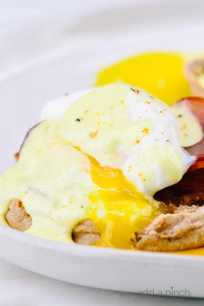 Eggs Benedict Recipe - Toasted English muffins topped with ham, bacon, or Canadian-style bacon, and poached eggs and then drizzled with hollandaise sauce make this a favorite brunch recipe. // addapinch.com