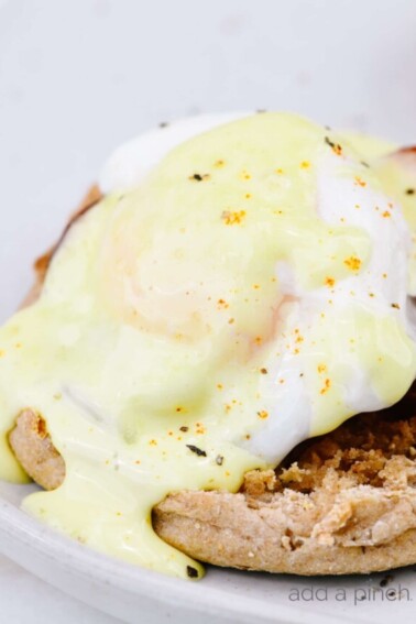 Hollandaise is drizzled over top of English muffin topped with poached egg and Canadian bacon.