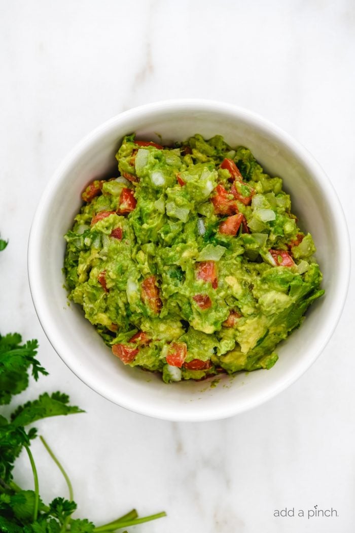 Guacamole Recipe - This simple guacamole comes together in less than 5 minutes and is full of fresh ingredients! Delicious dip and topping to so many dishes! // addapinch.com