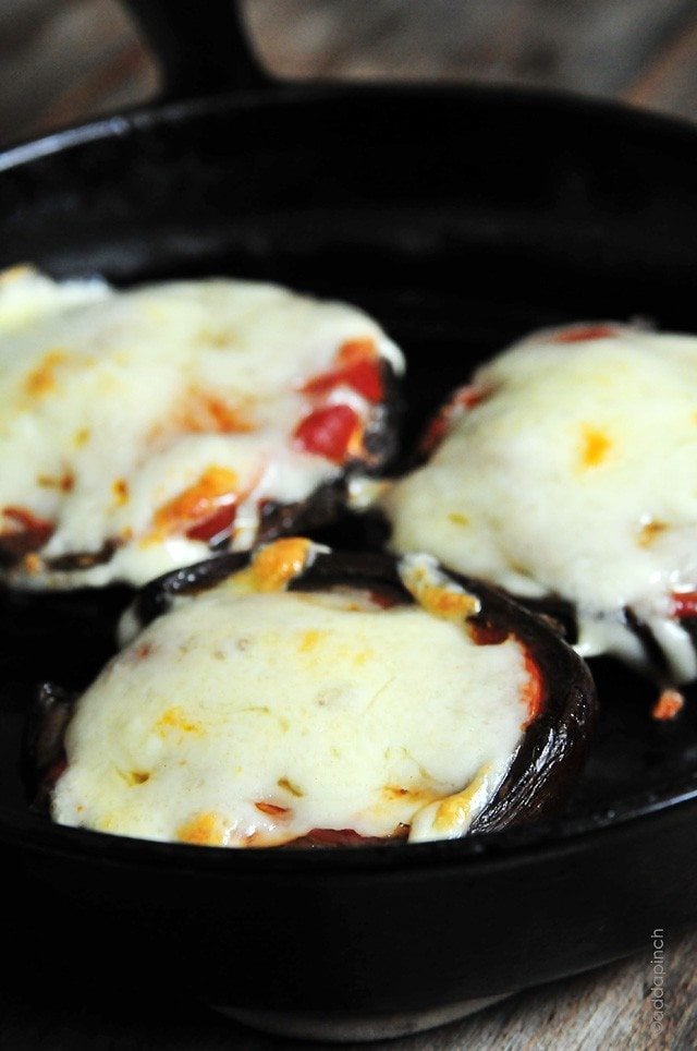 Skillet filled with mushrooms that are stuffed with filling topped with melted cheese // addapinch.com