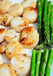 Seared scallops and asparagus on a white platter. // addapinch.com