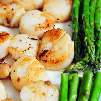 Seared scallops and asparagus on a white platter. // addapinch.com