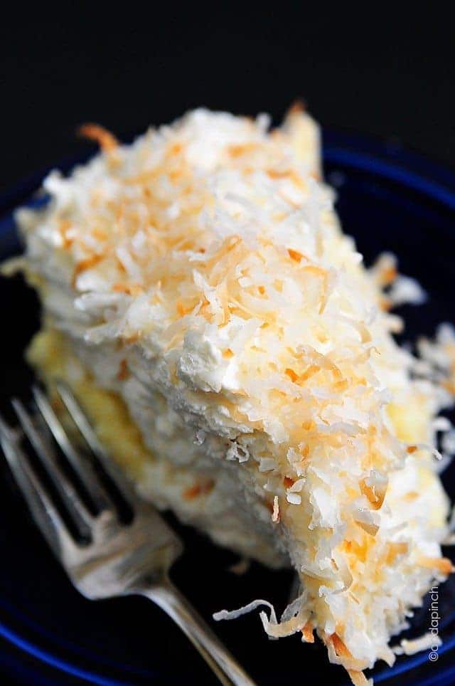 Photo of coconut cream pie with toasted coconut topping with fork on a blue plate.