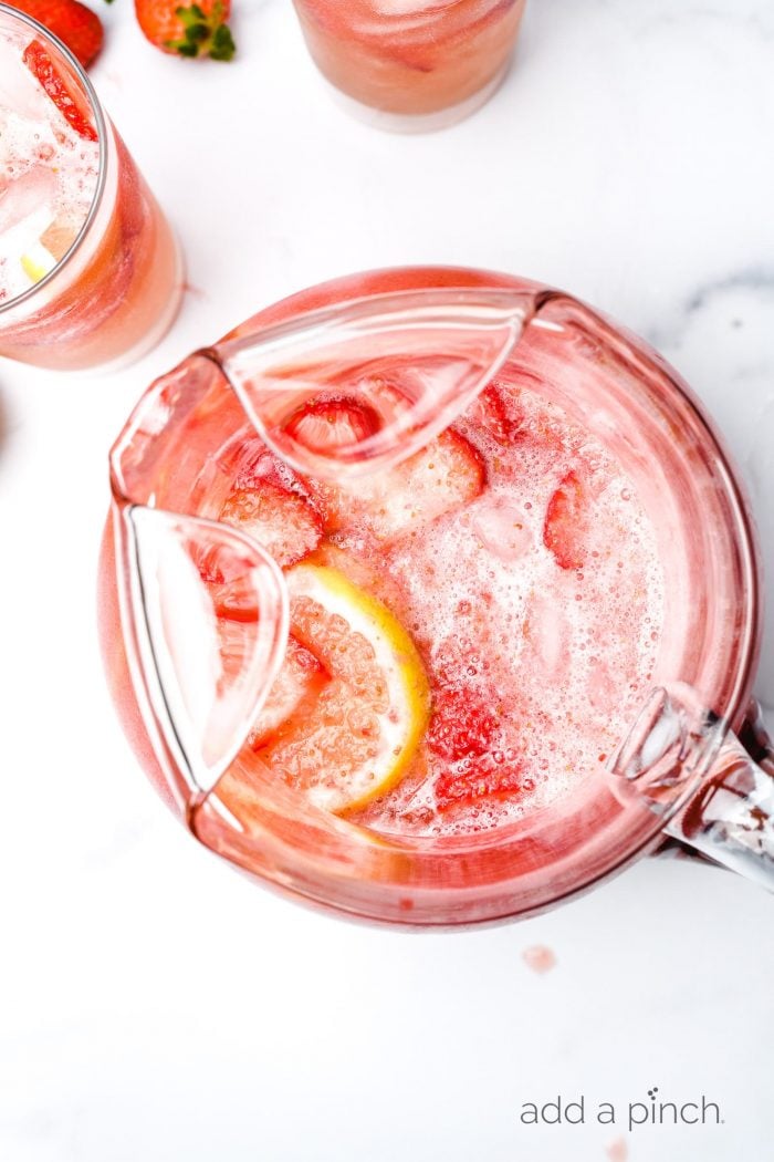 White counter with strawberry lemonade with ice and lemons  // addapinch.com