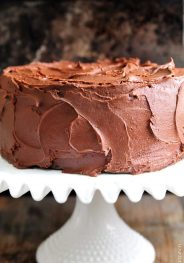 Amazing chocolate cake photographed with rich chocolate buttercream frosting on a white cake stand // addapinch.com