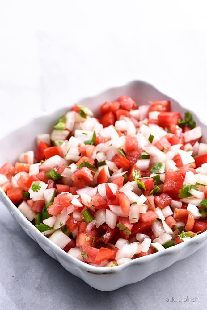 White serving bowl with mound of freshly chopped Pico de Gallo, all on marble surface // addapinch.com