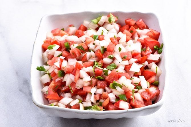 Fresh cilantro tops a white bowl full of fresh Pico de Gallo // addapinch.com