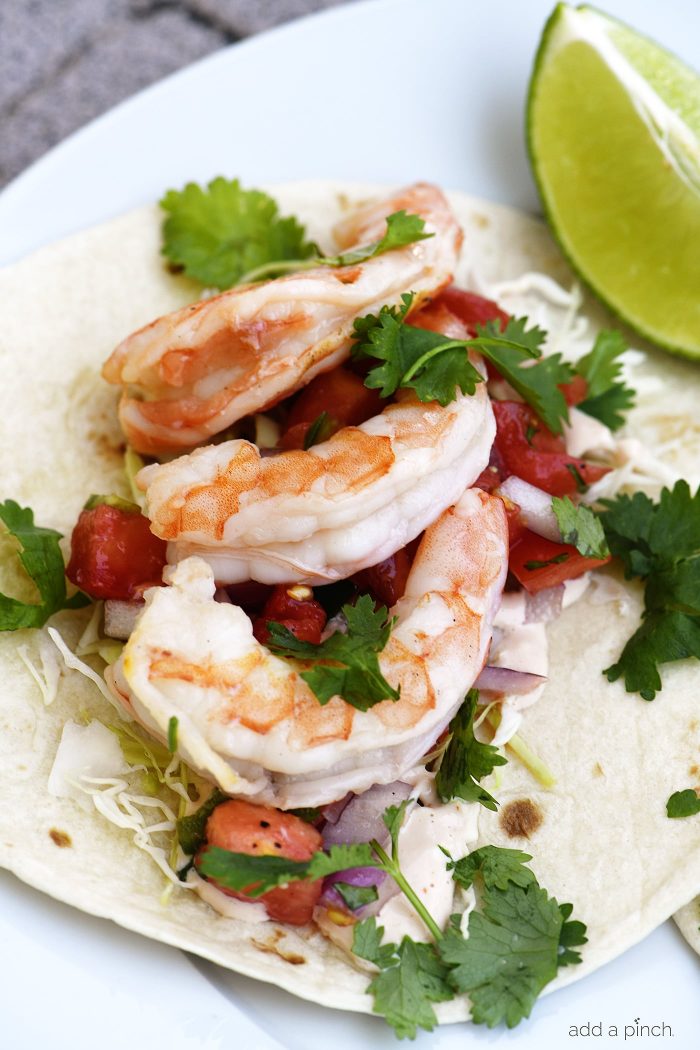 Shrimp Tacos with fresh herbs, cabbage, pico de gallo on a flour tortilla// addapinch.com