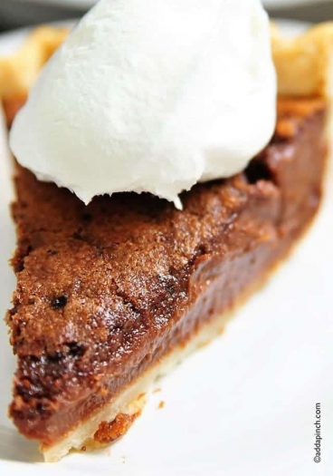 Photo of a slice of chocolate chess pie topped with whipped cream.