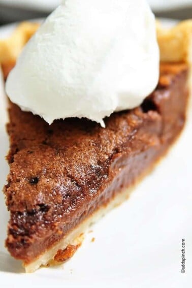 Photo of a slice of chocolate chess pie topped with whipped cream.