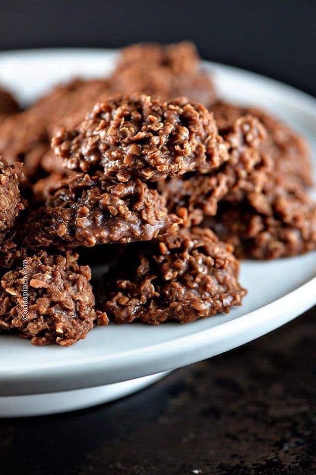 Close photograph of chocolate, peanut butter, and oat boiled treats on a white platter. // addapinch.com