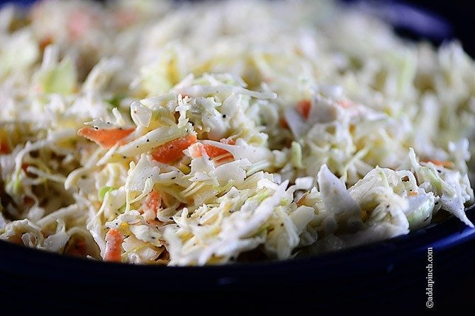 Side view of blue bowl holding coleslaw with carrots and cabbage // addapinch.com