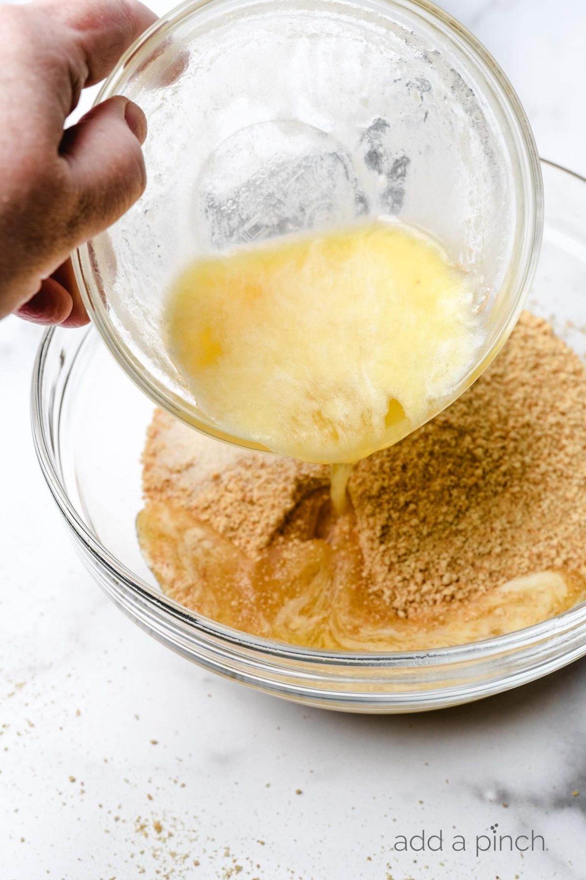 Melted butter is poured into graham cracker crumb and sugar mixture to make a crust.