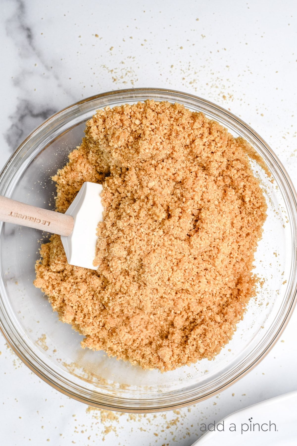 Melted butter is combined with graham crackers and sugar to form crust mixture.