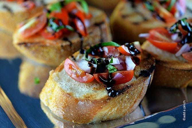 Grilled toast with tomato bruschetta topping and balsamic glaze on a silver tray.