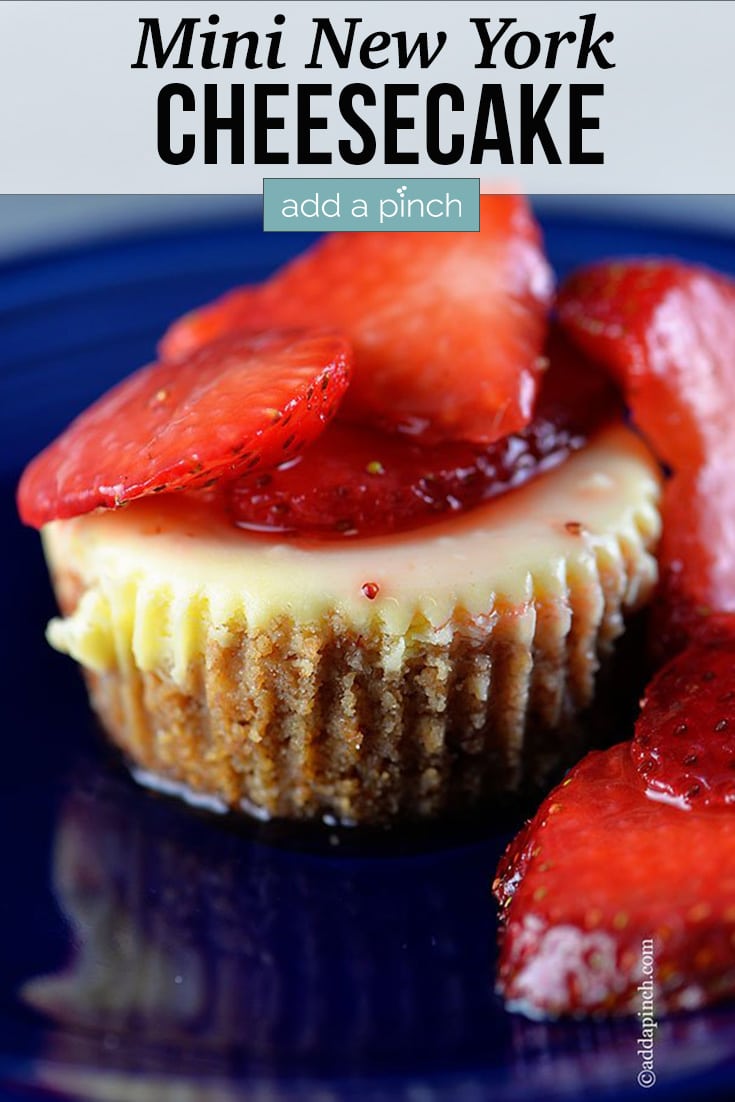 Mini New York Cheesecake topped with sliced strawberries on blue plate - with text - addapinch.com