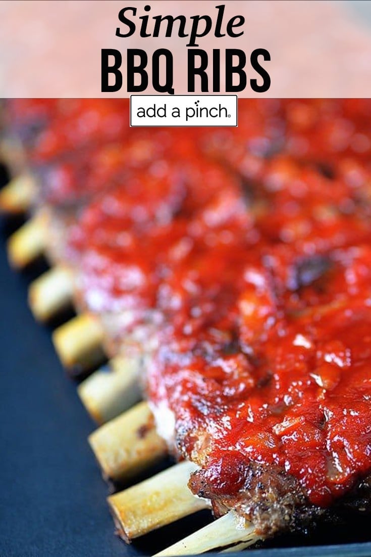 Rack of bbq ribs topped in BBQ Sauce, on a metal pan - with text - addapinch.com