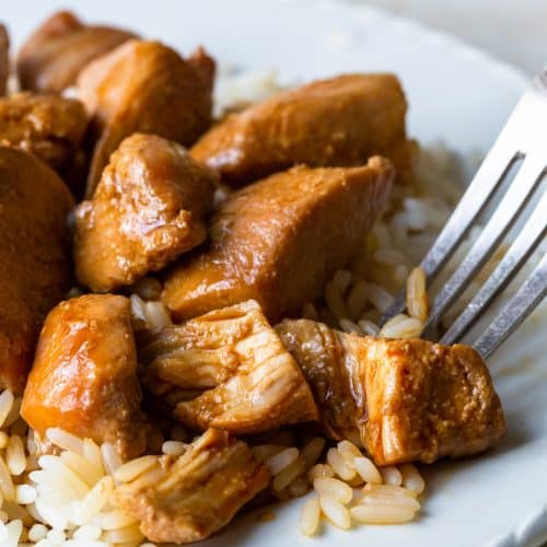 Cooked chicken teriyaki and rice on a white plate.