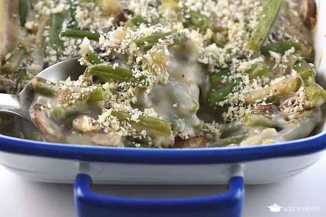 Panko tops creamy Green Bean Casserole that's being spooned out of blue rimmed white casserole dish 